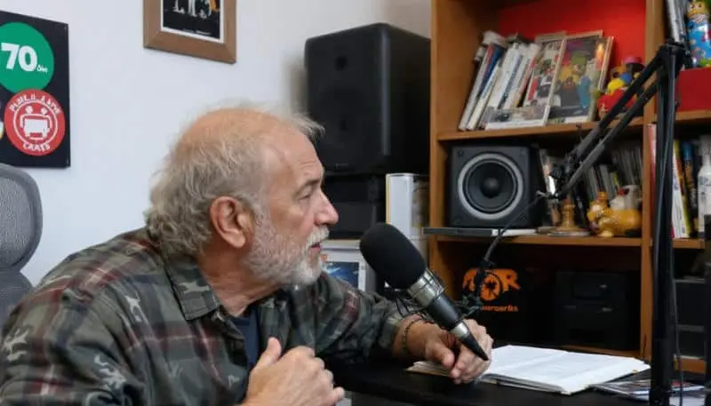 Un señor mayor graba un podcast en casa.